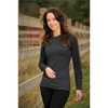 A woman wearing a long-sleeve, charcoal grey t-shirt standing near a wooden fence in an outdoor setting.