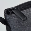 A drink bottle cooler in dark grey fabric with a zip closure and a branded tab.