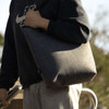 A grey recycled felt tote bag is being held by a person wearing a black hoodie and grey pants.