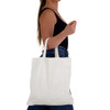 A person holding a plain white short handle bamboo tote bag, with a simple design and one logo visible.