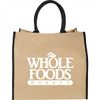 A large jute tote bag in natural tan with black handles and a logo on the front.