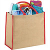 A large jute tote in natural colour with red trim, filled with a drink bottle, magazines, sunglasses, and a towel.