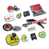 A collection of colourful lapel badges in various shapes, including animal, logo, and event-themed designs, with pins.