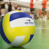 A volleyball featuring blue and yellow panels, with a logo, placed on a green indoor court.
