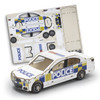 A model car in white with blue and yellow police markings, alongside its cardboard assembly sheet.