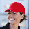 A red heavy acrylic sandwich cap with a contrasting trim, worn by a smiling woman. The cap has a logo.