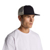 A navy trucker cap with a contrasting beige mesh back, modelled by a man wearing a white t-shirt.