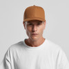 A brown canvas cap with a structured design and a logo, worn by a model in a white T-shirt.