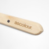 A wooden palette knife with a rounded end and a branding logo on the handle.