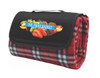 A folded red check picnic rug featuring a black canvas flap with a logo, showcasing a fruit graphic.