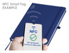 A navy blue A5 notebook with an NFC smart tag feature, featuring a logo. A phone displays NFC detection.