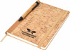 A cork-covered A5 notebook with an elastic band and a pen, featuring a logo on the front.
