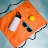 A drink bottle, a yellow ball, blue sunglasses, and an orange drawstring bag are arranged together in the image.