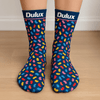 A pair of navy socks decorated with colourful bean-shaped patterns, featuring a logo at the top.