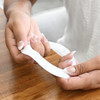A white silicone wristband held between hands, designed as a promotional product with a logo.