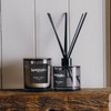 A Keepsake candle and diffuser set in black, featuring a whiskey and orange scent, displayed on a wooden surface.