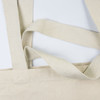 A beige tote bag with textured straps and a simple design, featuring a logo.
