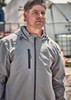 A light grey unisex packable rain jacket features a front pocket and a hooded design. The model is wearing it outdoors.
