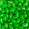 A close-up of shiny green mini jelly beans, displayed in abundance with a glossy surface.