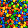 A mix of assorted colour M&M's, featuring blue, green, red, yellow, orange, and black choc beans.
