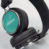 Bluetooth headphones with a teal ear cup, black padding, and an adjustable band. Features a logo on the side.