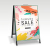 A double-sided metal A-frame sign featuring colourful abstract patterns and a branding logo.