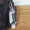 A clear 55ml hand sanitiser in a plastic bottle with a carabiner, featuring a logo, attached to a black bag.
