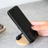 A black phone is mounted on a wooden stand, showcasing a magnetic car phone holder design.