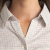 A close-up of a women's button-up shirt featuring a check pattern in light colours and a collar.