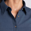 A close-up of a women's button-up shirt in dark blue, featuring a collar and button details. It has a logo.