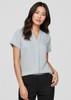 A light blue women's short sleeve button-up shirt displayed on a model, featuring a v-neckline and rolled sleeves.