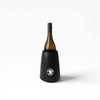 A black wine cooler holds a bottle of wine, featuring a circular logo on the front.