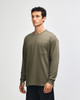 A long-sleeve, olive green t-shirt featuring a pocket and a logo, modelled by a young man.