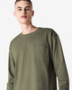 A model wearing an olive green American Apparel Super Heavyweight T-Shirt with a pocket. The shirt features long sleeves.