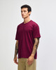 A maroon heavyweight t-shirt on a model, featuring a rounded neckline and short sleeves, with a logo present.