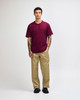 A model wearing a maroon heavyweight T-shirt and olive green cargo pants, featuring a logo.