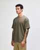A green American Apparel super heavyweight t-shirt displayed on a model standing upright, featuring a round neckline.