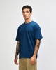 A model wearing a dark teal oversized T-shirt with short sleeves. The shirt has a simple design and a logo.