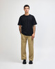 A model wears a black American Apparel Super Heavyweight T-Shirt paired with olive-green trousers and white sneakers.