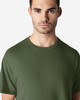 A green Gildan Light Cotton T-Shirt displayed on a model, featuring a simple design and a logo.