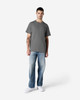 A grey Gildan Light Cotton T-Shirt worn by a man, paired with light blue jeans and white shoes.