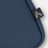 A soft-touch laptop sleeve in deep navy with a small branded tag on the edge.