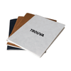 A set of three A5 notebooks in white, black, and brown, featuring a logo, placed on a desk with a coffee cup.