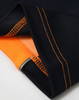 A close-up of a navy polo shirt featuring orange detailing and visible stitching on the collar and hem.