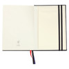 An open diary featuring smooth cream pages with a black cover and a ribbon bookmark in red and blue.