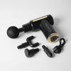 A black and gold massage gun with multiple attachments and a charging cable. It features a logo on the handle.