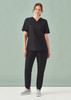 A black women's V-neck scrub top paired with matching pants, modelled by a woman against a light background.