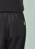 A close-up of black women's jogger scrub pants featuring a back pocket and elastic waistband.