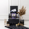 A stylish black gift box containing gourmet snacks, a picnic blanket, and packaged treats, featuring a decorative arrangement.