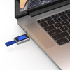 A silver LED flash drive with a blue pull tab is plugged into a laptop's USB port.